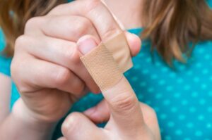 child putting a bandage on a cut finger