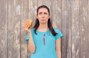 clumsy woman staining her shirt with ketchup sauce