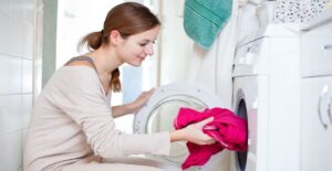 Woman putting laundry in an empty dryer