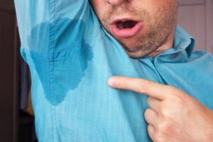 man standing with his arm up pointing at visable sweat stain